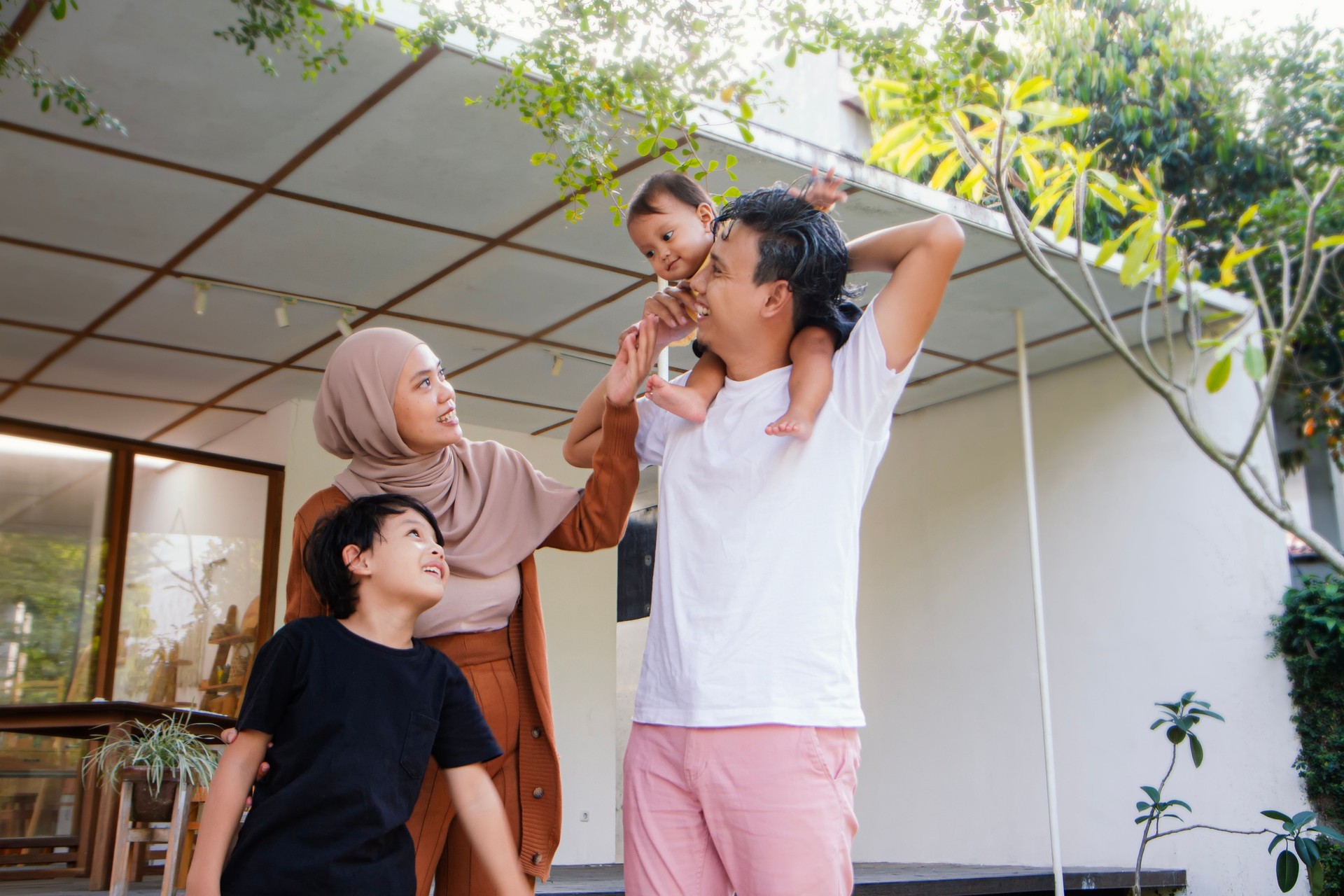 Asian Muslim Family having fun time at home. Asian family with little kids daughter playing together in house backyard outside. Happy family time.